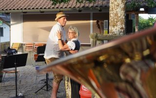 zwei Tanzende zwischen Notenständern, Baum und dem Trichter einer Tuba