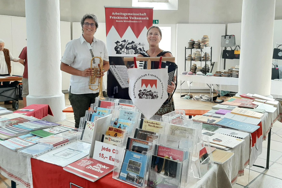 2 Personen am Infostand zwischen Büchern und Transparenten